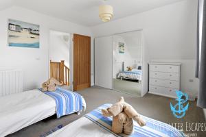 a bedroom with two beds and a teddy bear on the floor at Boundary Cottage - Spacious Homely Cottage With Log Burner and Garden in Marldon