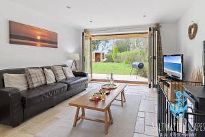 a living room with a black couch and a table at Boundary Cottage - Spacious Homely Cottage With Log Burner and Garden in Marldon