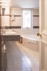 a bathroom with a tub and a sink and a window at Patagonia Plaza Hotel in San Martín de los Andes