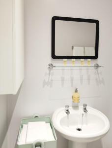 a white bathroom with a sink and a mirror at Portrush by the Sea - 5 West Beach in Portrush