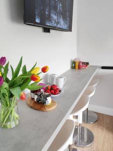 a kitchen counter with a table with a vase of flowers at Portrush by the Sea - 5 West Beach in Portrush