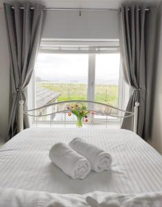 a bed with two towels on it with a window at Portrush by the Sea - 5 West Beach in Portrush