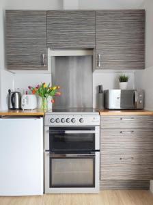 a kitchen with a stove and a microwave at Portrush by the Sea - 5 West Beach in Portrush