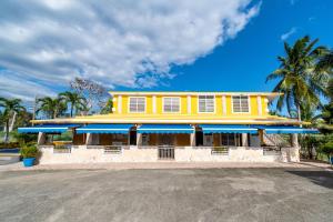 una casa amarilla con sombrillas azules delante de ella en Casamares Private Room Mar with Pool and Jacuzzi 5 min to Boqueron and Beaches en Cabo Rojo