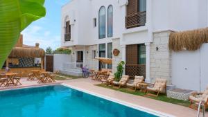 a villa with a swimming pool and tables and chairs at Wind Of Alaçatı Adult Only 13 in Çeşme