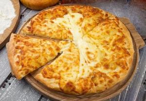 a cheese pizza on a plate on a table at Guesthouse Latphari in Ushguli