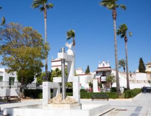 una statua di fronte a un edificio con palme di Apartamento Turístico Damajuana a Espartinas