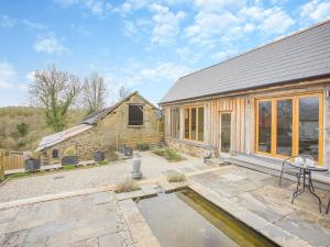 une maison avec un étang en face de celle-ci dans l'établissement Olive Barn, à Witheridge