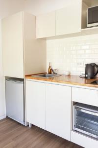 ブラガドにあるLA CALMA - Eco Lodge Ruralのシンクと冷蔵庫を備えた白いキッチン +4枚の写真