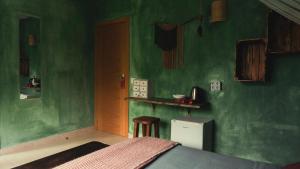 1 dormitorio con paredes verdes, 1 cama y 1 taburete en Hostal Esfigueral, en Playa Es Figueral 30 fotos más