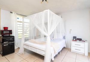 a white bed with a canopy in a bedroom at ATOAS - Lovely Vacation Retreat with Pool and Jacuzzi 5 min to Boqueron and Beaches in Cabo Rojo