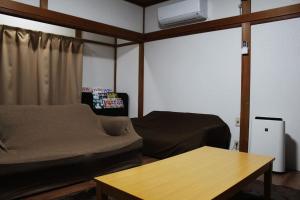 a living room with a bed and a table at JR福井駅東口から徒歩7分(550m)。一棟貸切民泊トリプレッツ in Fukui