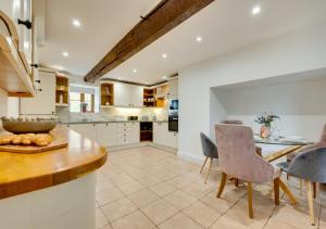 a kitchen with white cabinets and a table and chairs at Bythynnod Aderyn Cottages in Cemmaes