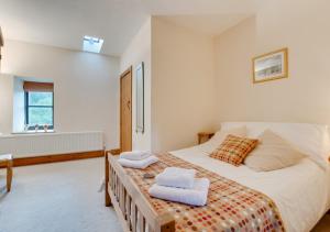 a bedroom with a large bed with towels on it at Bythynnod Aderyn Cottages in Cemmaes