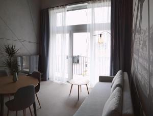 ein Wohnzimmer mit einem Sofa, einem Tisch und einem Fenster in der Unterkunft Wroclove Airport Loft in Breslau