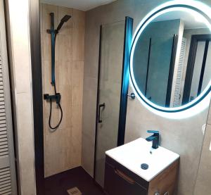 ein Bad mit einer Dusche, einem Waschbecken und einem Spiegel in der Unterkunft Wroclove Airport Loft in Breslau