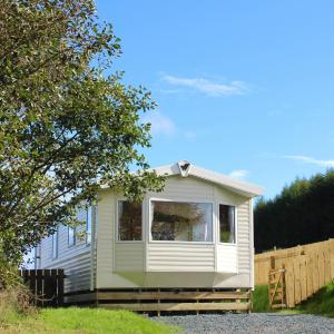 una casita verde y blanca en un patio en Crannich Holiday Caravans en Killichronan