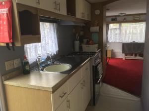 uma cozinha com um lavatório e um fogão em The Caravan at Loggans Lodge em Hayle