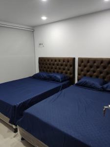 2 camas en una habitación con sábanas azules en SAN FELIPE CASA QUINTA, en Ibagué