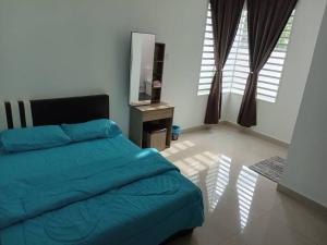 a bedroom with a blue bed and a television at EMERALD VILLA HOMESTAY DUNGUN in Batu Lima
