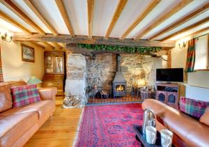 a living room with a couch and a stone fireplace at Cae Ceiniog in Dolgellau