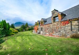 an old stone house with a grass yard at Cae Ceiniog in Dolgellau