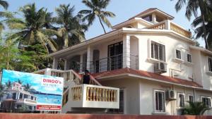 um homem de pé na varanda de uma casa branca em Dinoos Sea View em Malvan