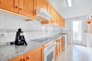 una cocina con armarios de madera y una batidora en una encimera en Casa en playa con piscina Novamar, en Santa Pola