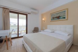 a bedroom with a bed and a desk and a window at Star Paradise Hotel in Neos Marmaras