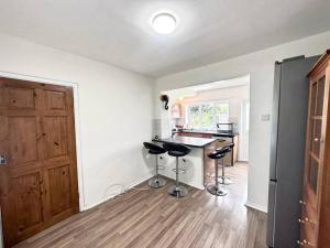 a kitchen with a counter and stools in a room at Spacious 3-Bed House with car park near Heathrow in Hounslow