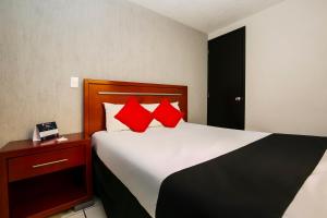 a bedroom with a large bed with red pillows at Capital O Hotel Victoria Morelia in Morelia