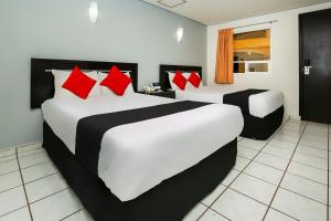 a bedroom with a large white bed with red pillows at Capital O Hotel Victoria Morelia in Morelia