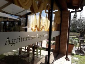a window of a restaurant with chairs and a sign at Agriturismo Lupo Cerrino in Tarquinia