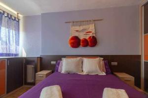 El Campus de Zamora في سمورة: غرفة نوم بسرير ارجواني مع وجود سلالتين حمرا على الحائط