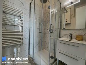 W łazience znajduje się szklana kabina prysznicowa i umywalka. w obiekcie Albert 1er w mieście Vichy