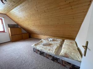 a bed in a room with a wooden ceiling at Chata Fialka in Veľký Slavkov