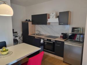 a kitchen with black cabinets and a table with pink chairs at TWO Self-Check-In, 3km freeway, Free-Parking Playstation in Wolfpassing an der Hochleithen