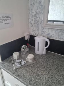 a kitchen counter with a coffee pot and cups on it at Leeds House Guest House in Bridlington