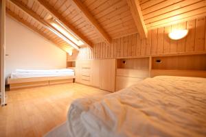 a bedroom with two beds in a room with wooden walls at Majon Fior de Bosch 2 in Campitello di Fassa