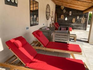 Maillane的住宿－La maison des Amis，庭院配有2把红色椅子和桌子
