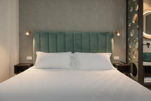 1 cama grande con sábanas blancas y cabecero verde en Hotel Sole, en Riccione