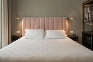 a bedroom with a large white bed with a pink headboard at Hotel Sole in Riccione