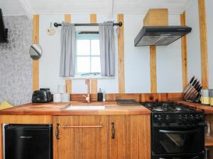 a kitchen with a black stove and a sink at Elsie's Hut in Bude