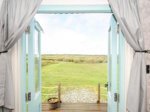 an open door to a porch with a view of a field at Elsie's Hut in Bude