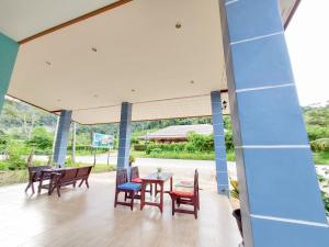 un patio con sillas, mesas y una pared azul en Khao Sok Backpacker Hostel, en Khao Sok