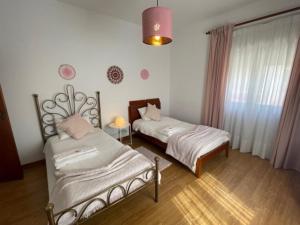 1 dormitorio con 2 camas, ventana y lámpara en Quinta do Carvalheiro, en Sobral de Monte Agraço