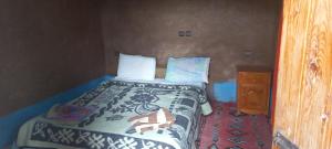a small bedroom with a bed and a night stand at Auberge Amazigh in Tamtetoucht