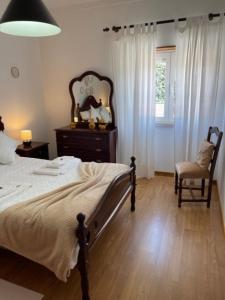 a bedroom with a bed and a chair and a window at Quinta do Carvalheiro in Sobral de Monte Agraço