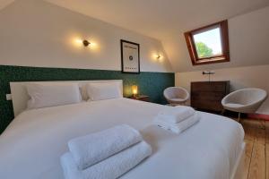 a bedroom with a white bed with two towels on it at La Cabane de Milo - Typical Honfleur fisherman's house - 2 bedrooms in Honfleur