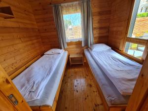 two beds in a wooden room with two windows at Domki Gościniak in Rewal